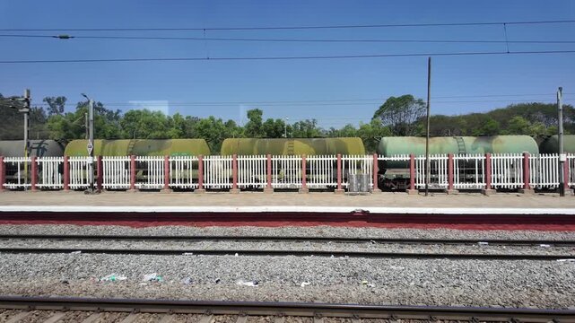 POV from moving train passing freight tanker wagons at railway station, transport and logistics concept