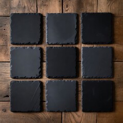 Fototapeta premium A set of nine square black slate tiles arranged in a grid pattern on a wooden surface, ideal for showcasing laser engraving or other custom designs, offering a clean and elegant presentation.
