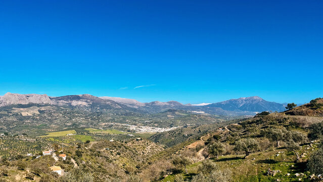 Wide view over a green valley with a white andalucian village. Colmenar, Malaga, Andalusia, Spain.