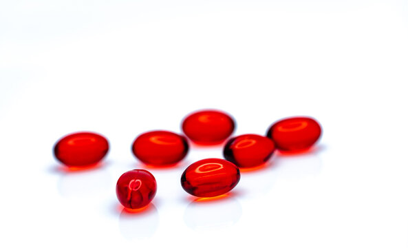 Red soft gel capsule pills isolated on white background. Pile of red soft gelatin capsule. Vitamins and dietary supplements concept. Pharmaceutical industry. Pharmacy drug store. Health care products.