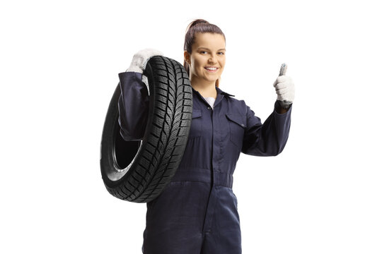 Female mechanic worker carrying a tire and showing thums up