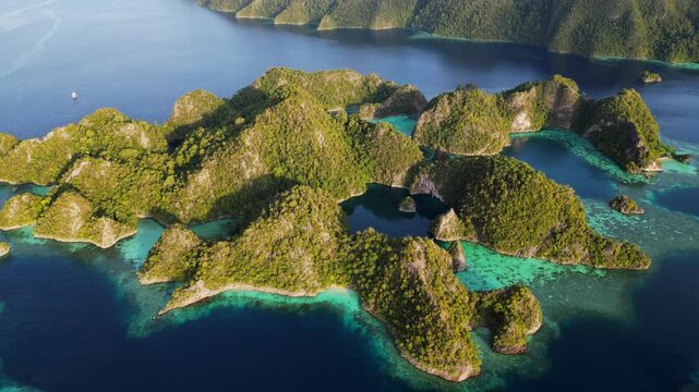 Drone footage, Panning around a cluster of high tropical islands in Raja Ampat with blue lagoons and shallow coral reefs.