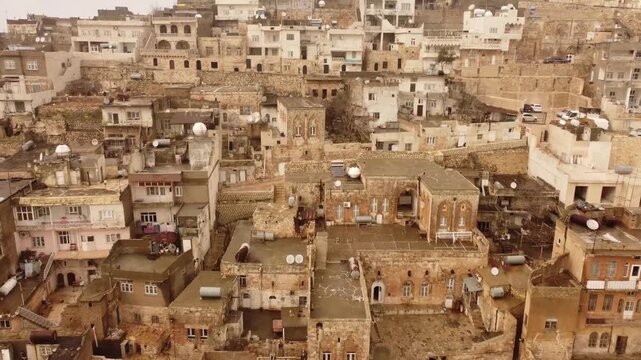 Aerial drone view of Mardin Turkey showing dense old city with layered stone buildings and narrow streets, historic urban texture, cultural heritage and travel destination