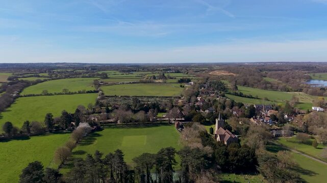 Hertingfordbury drone orbit reveals the full village, patchwork farmland, Panshanger Quarry and distant Hertford on a clear day, ideal for UK countryside, travel, and geography use.