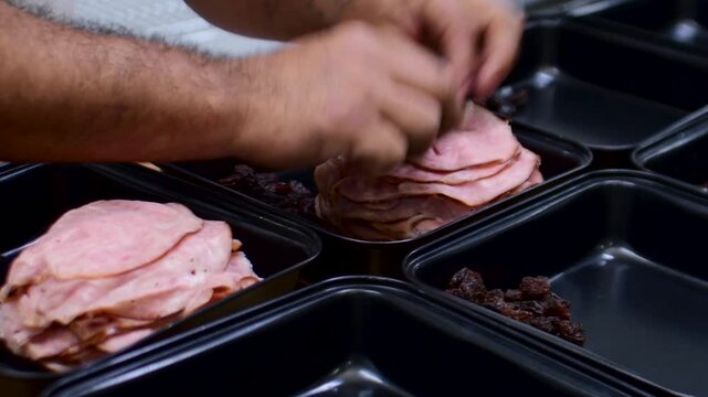 Hands preparing ham and raisin trays for festive dish assembly