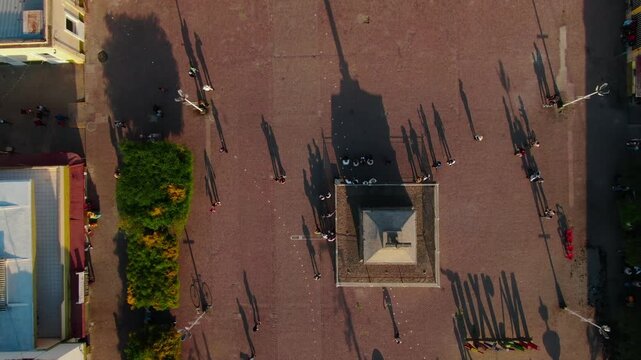 Top down view of plaza with central cross structure casting long shadows of people, geometric layout, Tuxpan Jalisco Mexico