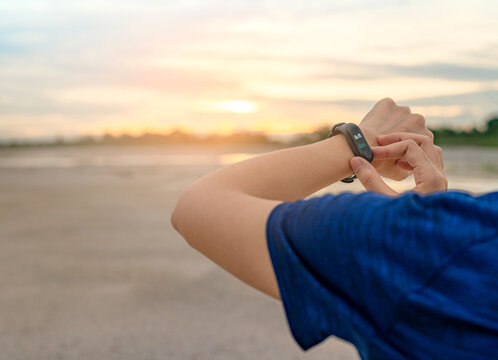 Woman touching smart fitness band after running, wearable device with heart rate monitor connected mobile app, healthy lifestyle. Activity tracking, workout performance and digital fitness technology.