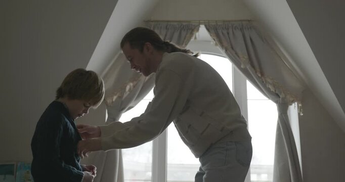 Man puts warm clothes on child. Dad help child to dress at home. 4K 10-bit