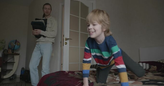 Man puts warm clothes on child. Dad help child to dress at home. 4K 10-bit