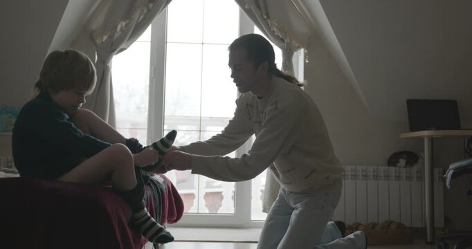 Man puts warm clothes on child. Dad help child to dress at home. 4K 10-bit