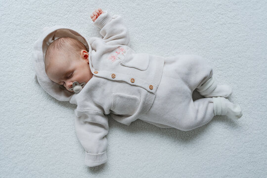 Infant lying on clean white background in minimal style.