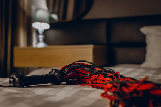 Braided flogger laid on bed with lamp in background