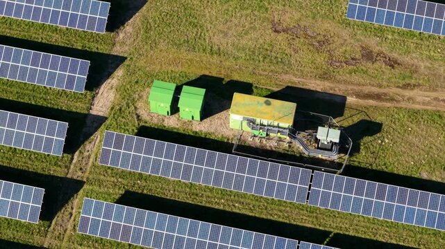 Top down aerial view of solar farm and electrical transformer units, photovoltaic panels for renewable energy generation and sustainable power infrastructure in UK countryside.