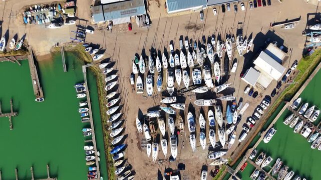 Top down aerial view of luxury yachts and sailing boats in marina near Felixstowe, UK, rotating drone shot of nautical vessels at dock in Suffolk harbor, leisure and travel lifestyle.