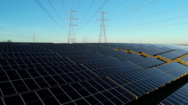 Aerial view of solar panel array and high voltage pylons in Tye, UK