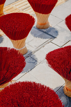 Rows of red incense bundles drying on stone pavement
