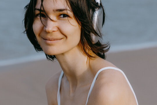 Young woman smiling wearing headphones by seaside