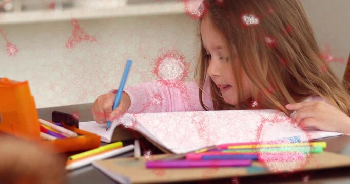 Drawing child in pink top at home table holding blue pencil with notebook and colored pencils