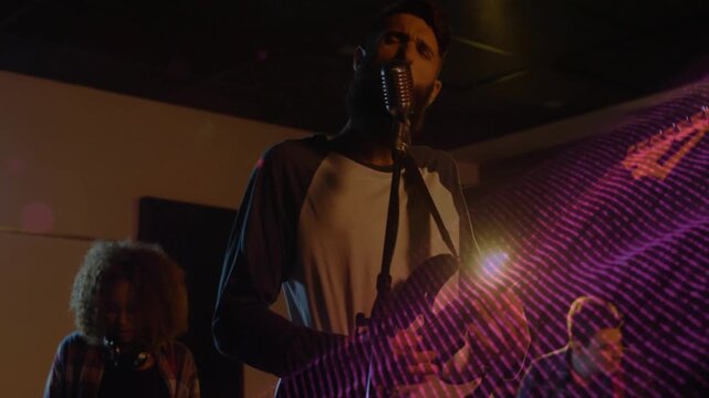 Lead singer strumming guitar and singing, camera pushing in, sparking purple overlay to show music