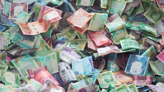 Close up vibrant pile of Qatari Riyal banknotes from the fifth series. Various colorful denominations 1, 10, and 50, showcasing Qatars modern currency and heritage. Charity box. Fundraiser. Lottery
