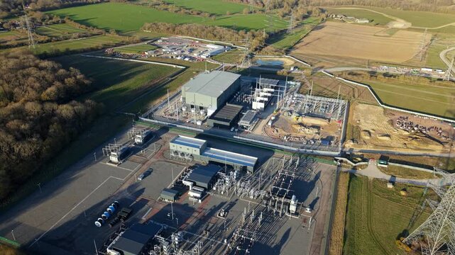 Close up aerial view of Bramford electrical substation near Ipswich, UK, showing high voltage transformers, busbars, and power line infrastructure.