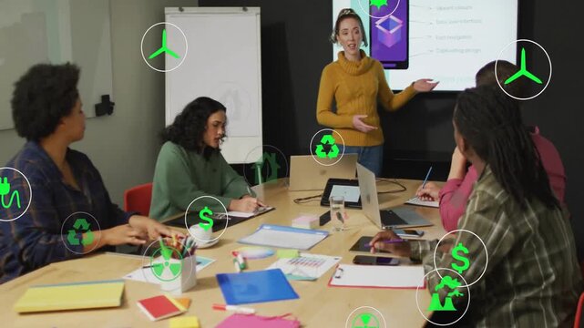 Presenter presenting green energy slides while colleagues taking notes and icons moving over table