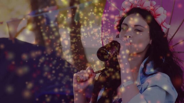 Woman bringing bottle to lips, sipping with umbrella, golden sparkles drifting over face, marketing
