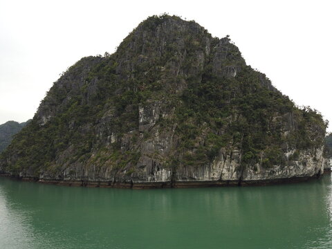 Limestone island in Ha Long Bay Vietnam with calm water