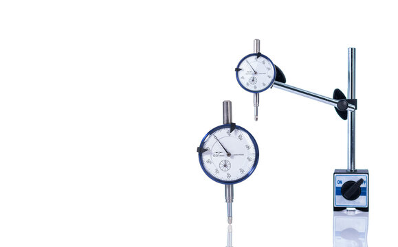 Dial gauge indicator on white background, precision measurement tool with analog scale for industrial inspection. Calibration accuracy and quality control in factory machining and engineering process.