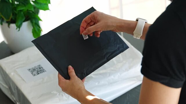 Person placing QR code label on parcel before shipping at home. Preparing package for delivery with digital tracking and logistics process concept.