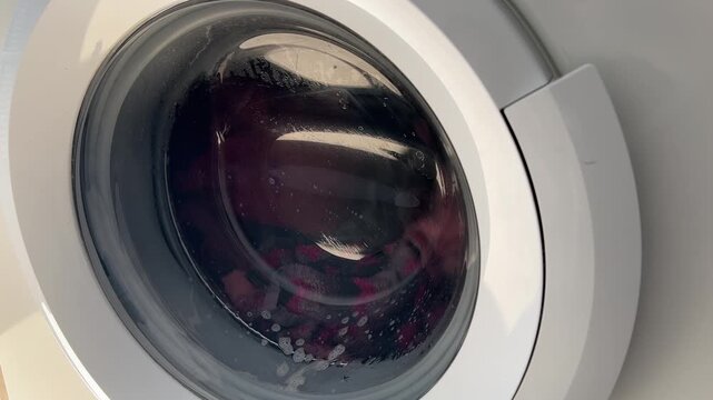 Ropa girando con espuma dentro de la lavadora