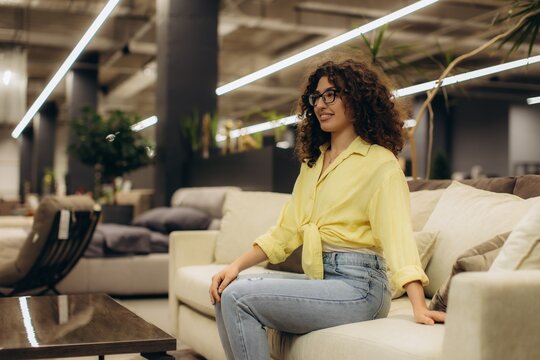 Woman trying out sofa in furniture showroom