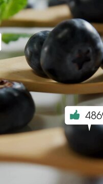 Vertical video: First bubble popping over berries on spoons, grouping, rising counts for engagement