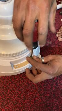 An electrician is fixing a brand new ceiling fan. 