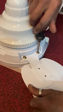 An electrician is fixing a brand new ceiling fan. 