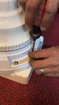 An electrician is fixing a brand new ceiling fan. 