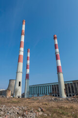 Elektrociepłownia EC2 w Łodzi w trakcie rozbiórki. Industrialna architektura z czerwono-białymi kominami i chłodniami kominowymi na tle błękitnego nieba. © smoku7979