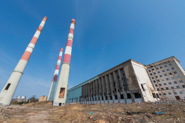 Elektrociepłownia EC2 w Łodzi w trakcie rozbiórki. Industrialna architektura z czerwono-białymi kominami i chłodniami kominowymi na tle błękitnego nieba. © smoku7979