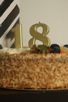 Gold number 18 candle on a delicious birthday cake with berries