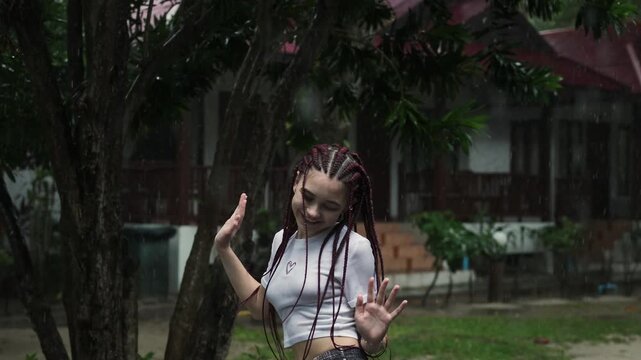 Teen girl with soft movement. Casual portrait of young woman dancing gently with modest smile in park