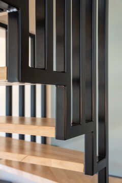 Photographie d&rsquo;un escalier en bois naturel avec structure moderne et rampe en m&eacute;tal noir, mettant en valeur un design int&eacute;rieur contemporain et &eacute;pur&eacute;.