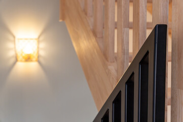 Fototapeta premium Photographie d’un escalier en bois naturel avec structure moderne et rampe en métal noir, mettant en valeur un design intérieur contemporain et épuré.