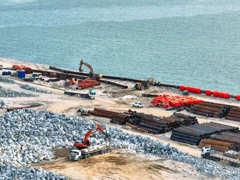 Construction progress on shipping port terminal through land reclamation. Global trade development, infrastructure engineering, and marine environmental sustainability efforts. Maritime infrastructure