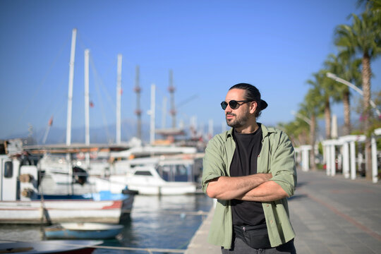 Portrait of a young contented man in the city port of sailing and motor yachts on a sunny day.