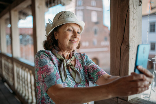 An elderly woman conducts a guided tour of an ancient castle. The pensioner examines historical artifacts at the exhibition, takes pictures on the phone