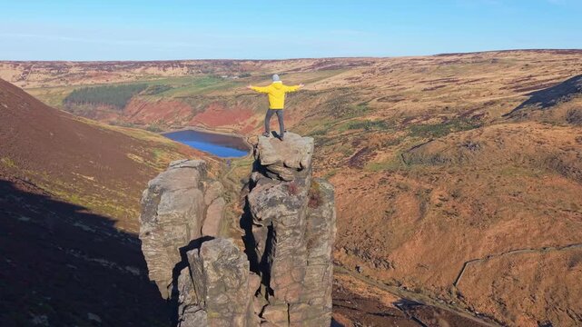 Drone POV of Man standing on the highly exposed rock. The Trinnacle is a remote and highly exposed rock formation in the Peak District near the town of Oldham at around 900ft in altitude.