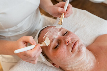 Woman receiving professional facial treatment with mask at spa