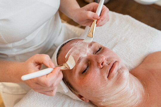 Woman receiving professional facial treatment with mask at spa