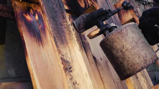 decorative burning of a wooden pallet for a street table with an old gasoline blowtorch