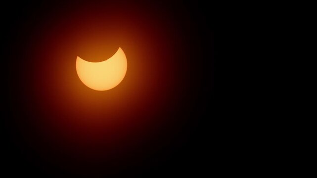 Stunning cinematic view of the partial solar eclipse on April 8, 2024. A glowing golden crescent sun shines brightly in the sky over Halifax, Nova Scotia, Canada during this rare astronomical event 4K